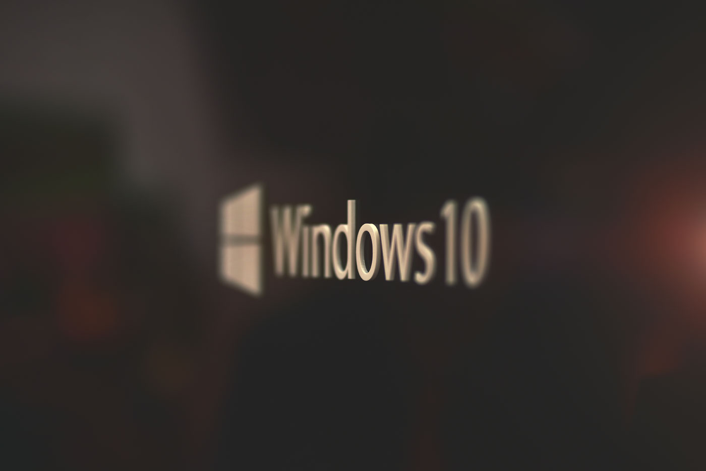 Windows 10 logo on a metallic surface in selective focus with warm tones indicating the End of Life update alert